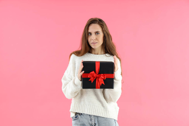 Attractive woman holds gift box on pink background - Foto, immagini