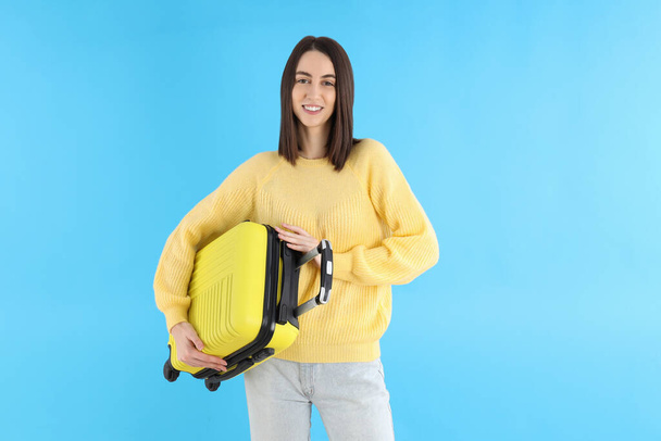 Attractive woman with travel bag on blue background - Photo, image