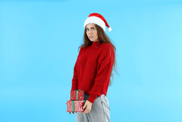 Attraente donna in cappello Santa tiene scatole regalo su sfondo blu - Foto, immagini