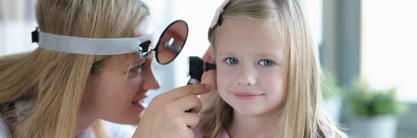 ENT médico mira a las niñas orejas con otoscopio primer plano - Foto, imagen