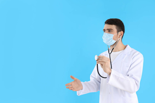 Young man doctor with stethoscope on blue background - Zdjęcie, obraz