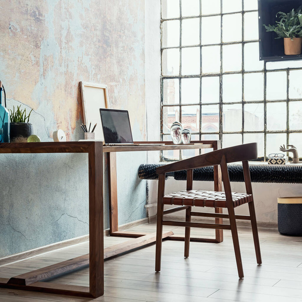 Interior design of stylish office space in loft apartment with wooden desk, chair, office supplies, laptop, plants and elegant accessories. Modern home office decor. Retro wall. Template. - Foto, Bild