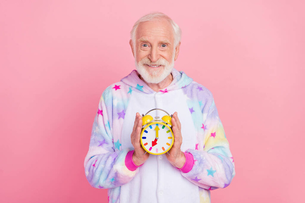 Photo of pretty handsome retired man nightwear overall smiling holding clock isolated pink color background - Φωτογραφία, εικόνα