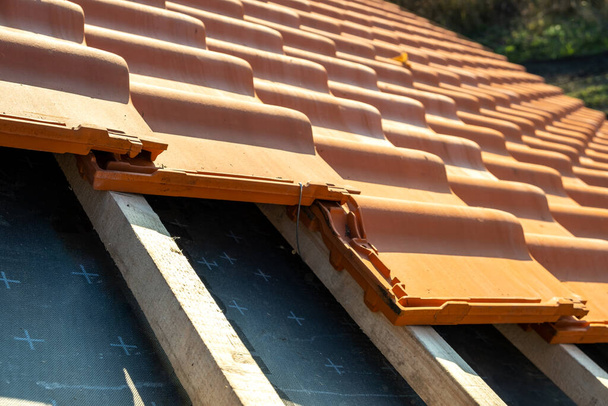 Chevauchement de rangées de tuiles de toiture en céramique jaune montées sur des planches de bois couvrant le toit du bâtiment résidentiel en construction - Photo, image