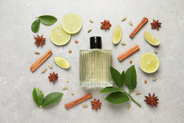 Flat lay composition with bottle of perfume, lime and spices on light grey background - Photo, Image
