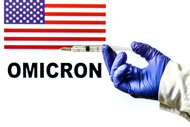 Ručně držená injekční stříkačka s kovidovou vakcínou. United States flag a Omicron covid varianta slovo napsané v pozadí - Fotografie, Obrázek