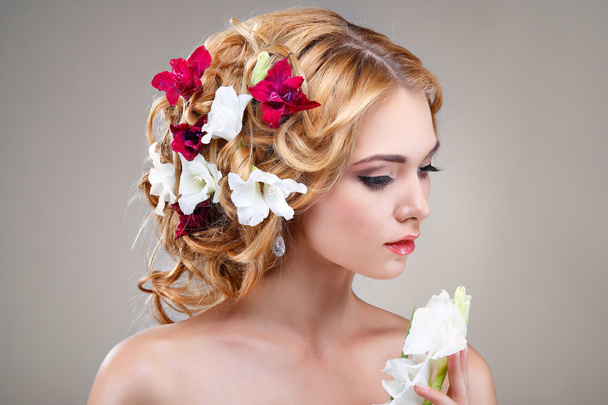piękna dziewczyna, na białym tle na światło - szary tło z varicoloured kwiatów w włosy, emocje, kosmetyki - Foto, afbeelding