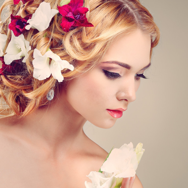 Beautiful  girl, isolated on a light - grey  background with varicoloured flowers  in hairs, emotions, cosmetics - Foto, imagen