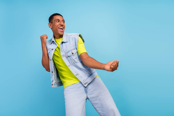 Photo of young cheerful afro guy have fun dance look empty space casual clothes isolated over blue color background - Zdjęcie, obraz