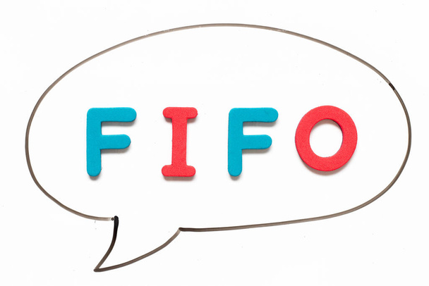 Letra del alfabeto con palabra FIFO (Abreviatura de first in first out) en dibujo a mano en línea negra como discurso de burbuja sobre fondo de pizarra blanca - Foto, imagen