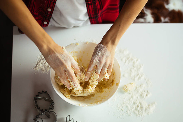 teenager's hands knead dough in bowl on table, top view. Flour, pastries. Hobbies and activities for child. Cooking at home. Unrecognisable person  - Photo, Image