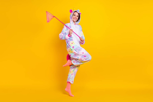 Full length body size photo woman in unicorn costume keeping pink net isolated bright yellow color background - Fotó, kép