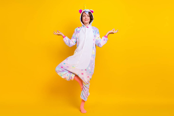 Full length body size photo woman in unicorn costume practising yoga isolated vibrant yellow color background - Foto, afbeelding
