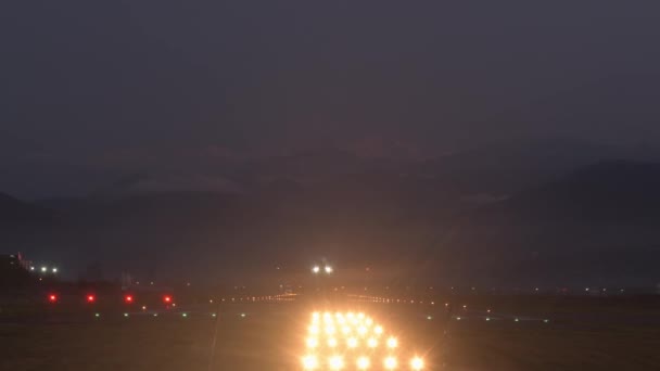 Статический вид Батумской взлетно-посадочной полосы аэропорта ночью с коммерческим вылетом самолета и кавказскими горами фона. Ночной полет самолёта с земли - Кадры, видео