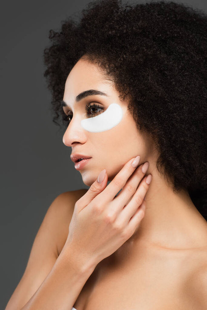 young african american woman in eye patch touching face isolated on grey - Photo, Image