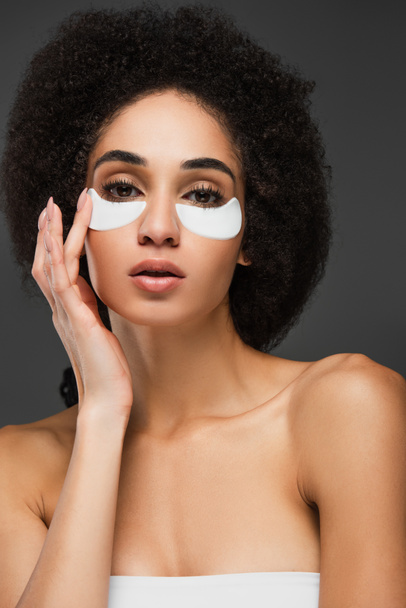 african american woman with naked shoulders touching eye patch on face isolated on grey - Zdjęcie, obraz