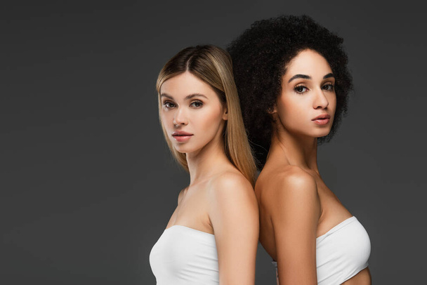 pretty interracial women with perfect skin looking at camera isolated on grey - Фото, зображення