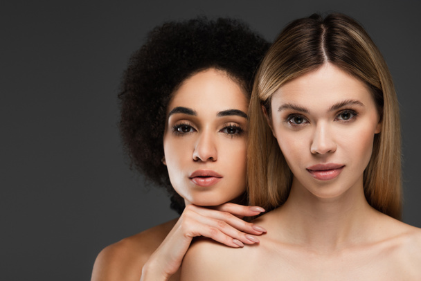 young and pretty multiethnic women with perfect skin and natural makeup looking at camera isolated on grey - Fotó, kép