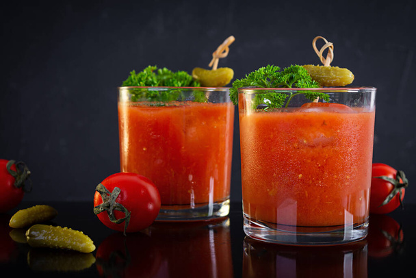 Koktajl alkoholowy Krwawa Mary na ciemnym tle. Klasyczny koktajl z sokiem pomidorowym i wódką - Zdjęcie, obraz