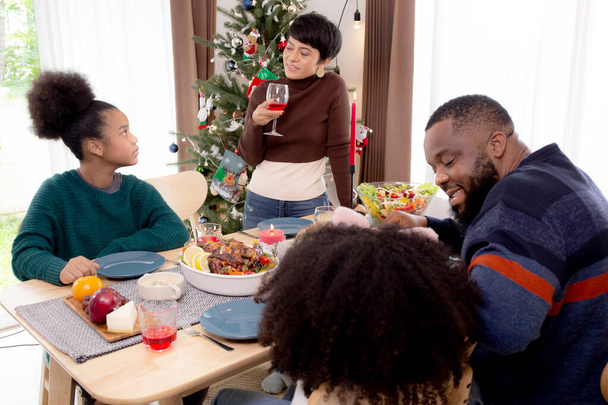 Boldog afrikai család eszik ételt vacsora ünnepi hálaadás este együtt otthon, apa és anya és gyermekek ünnepi party, miközben díszítő karácsonykor és újév ünnep. - Fotó, kép