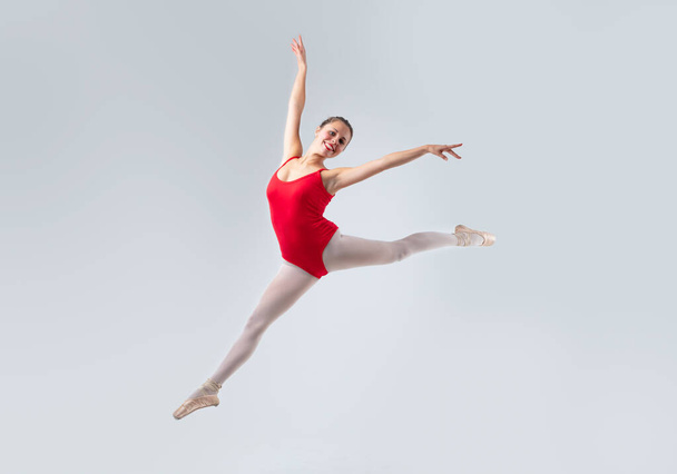 portret op een witte achtergrond van een klassieke danser die in een danspasje springt, in delicate harmonie lijkt te vliegen, maar discipline en spierbeheersing zijn nodig - Foto, afbeelding