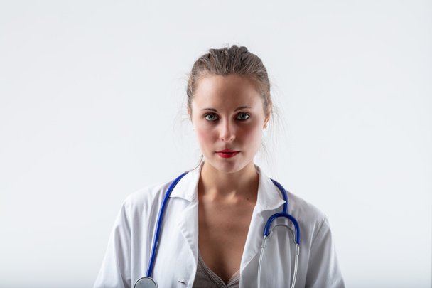 frontal and centered portrait of a very serious, attractive and intelligent young female doctor - Photo, Image