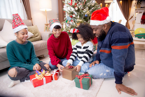 Glücklicher Familienvater und Mutter überreichen Geschenkbox mit Tochter zur Feier des Weihnachtstages zu Hause, Weihnachten mit Eltern, die Kinder mit aufgeregtem Haus überraschen, Danksagungsabend, Frohe Weihnachten. - Foto, Bild