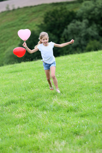Little girl running in field with balloons - Фото, изображение