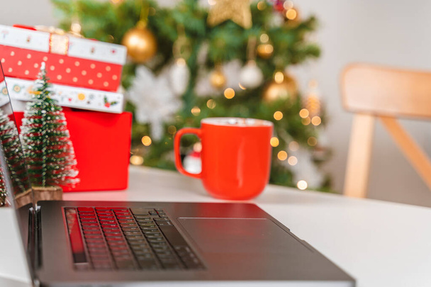 Selective focus on laptop keyboard with Christmas tree background - Photo, Image