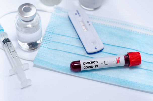 Tubo di prova con campione di sangue positivo del test Omicron COVID-19 e test rapido positivo covid-19 nel laboratorio medico. - Foto, immagini