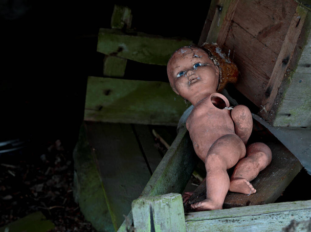 Μια παλιά εγκαταλελειμμένη κούκλα με σκισμένα άκρα. - Φωτογραφία, εικόνα