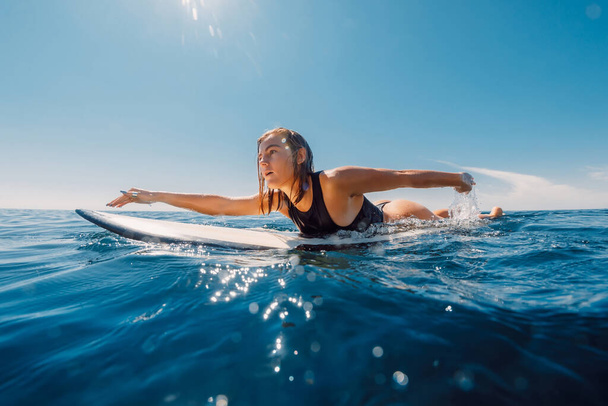 Surf girl rowing on surfboard. Attractive surfer woman in ocean and sunny day - Photo, Image