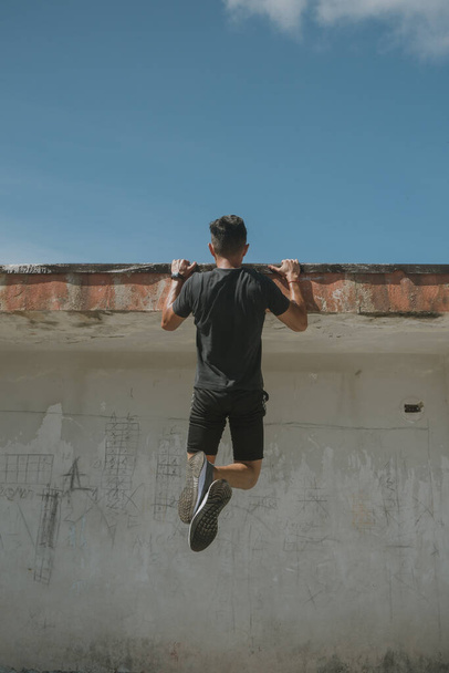A young handsome guy exercising on the roof of a building - Foto, imagen