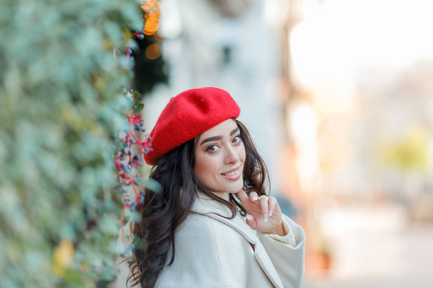 Kış tatili için Avrupa 'da yürüyen kırmızı bereli güzel bir kadının Noel sokak tarzı portresi. Kıvırcık saçlı şık manken yeni yıl alışverişi yapıyor. Samimi. - Fotoğraf, Görsel