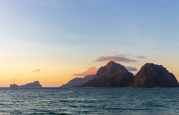 Scenic sunset on Philippines island, El Nido. Scenic evening landscape on sunset. Tropical coast with island and boats on background. Amazing seaside in twilight. Tropical tourism. Dramatic moody sky. Winter in tropics. - Photo, Image