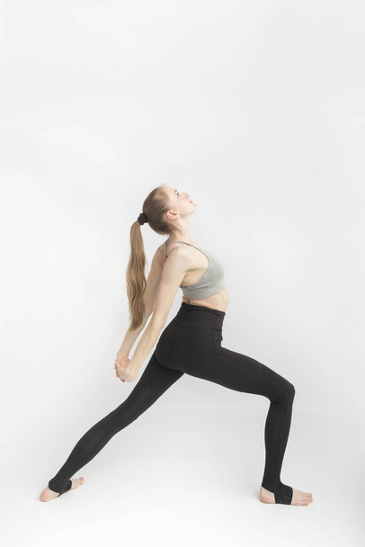 Young woman with sports figure is engaged in yoga. Yoga instructor side view on white background - Φωτογραφία, εικόνα