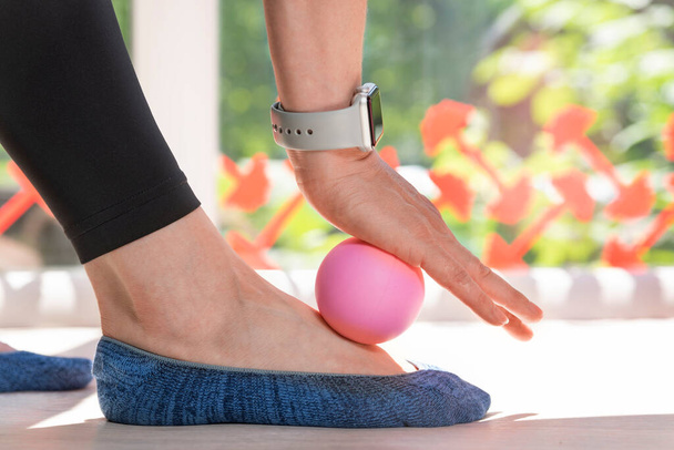 Girl using massage tool for foot massage. Exercise equipment for self-masage. Myofascial ball. Close up. - Photo, Image