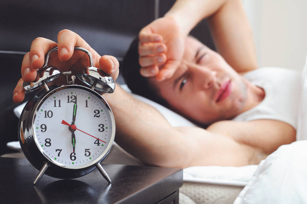 Man sleeping with alarm clock in foreground - Foto, Imagen