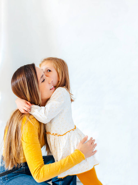 Young business woman hugging her daughter on white background. Young hispanic woman. Mum and daughter concept. - Φωτογραφία, εικόνα