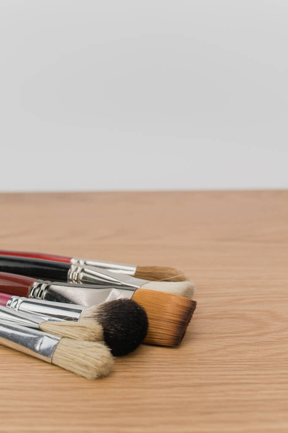 set of paintbrushes on a wooden tabletop with copy space - 写真・画像