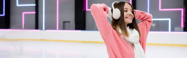 happy young woman in ear muffs and scarf on ice rink, banner - Fotografie, Obrázek