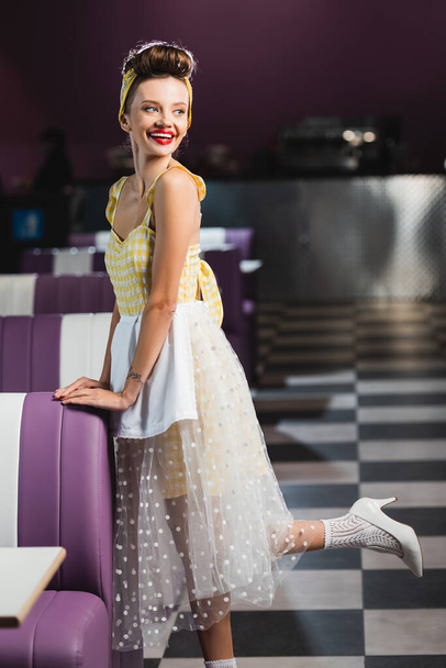 full length of pretty pin up woman smiling in cafe - Photo, image