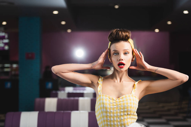 shocked pin up woman with retro hairstyle looking at camera  - Photo, Image