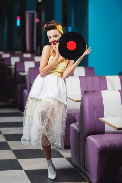 full length of happy pin up woman with red lips holding retro vinyl disc  - Photo, Image
