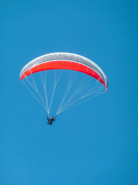 A vertical shot of a parachutist on the blue sky background - Fotó, kép