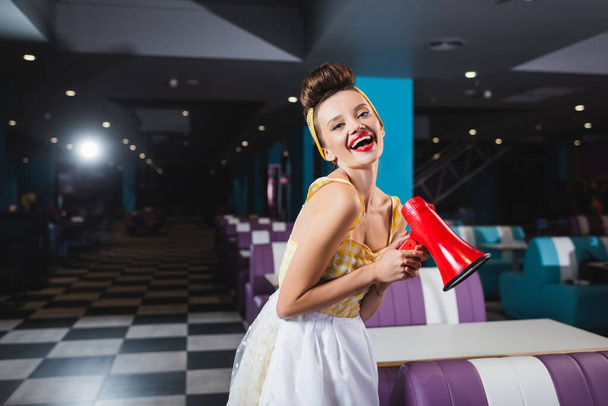 happy pin up woman with megaphone in cafe - Photo, Image