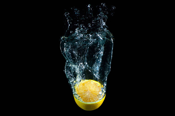 Halved lemon floating in water isolated on black background - 写真・画像