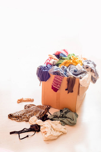 Pile of clothes in a large cardboard box and scattered things - Photo, image