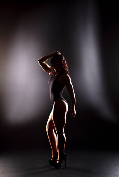 Forte femme bodybuilder fitness aux cheveux noirs et corps bronzé posant en studio - Photo, image