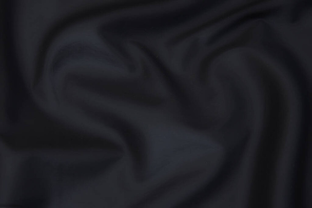 Close-up textuur van natuurlijk grijs of zwart weefsel of doek in dezelfde kleur. Stofstructuur van natuurlijk katoen, zijde of wol, of linnen textiel. Zwarte canvas achtergrond. - Foto, afbeelding